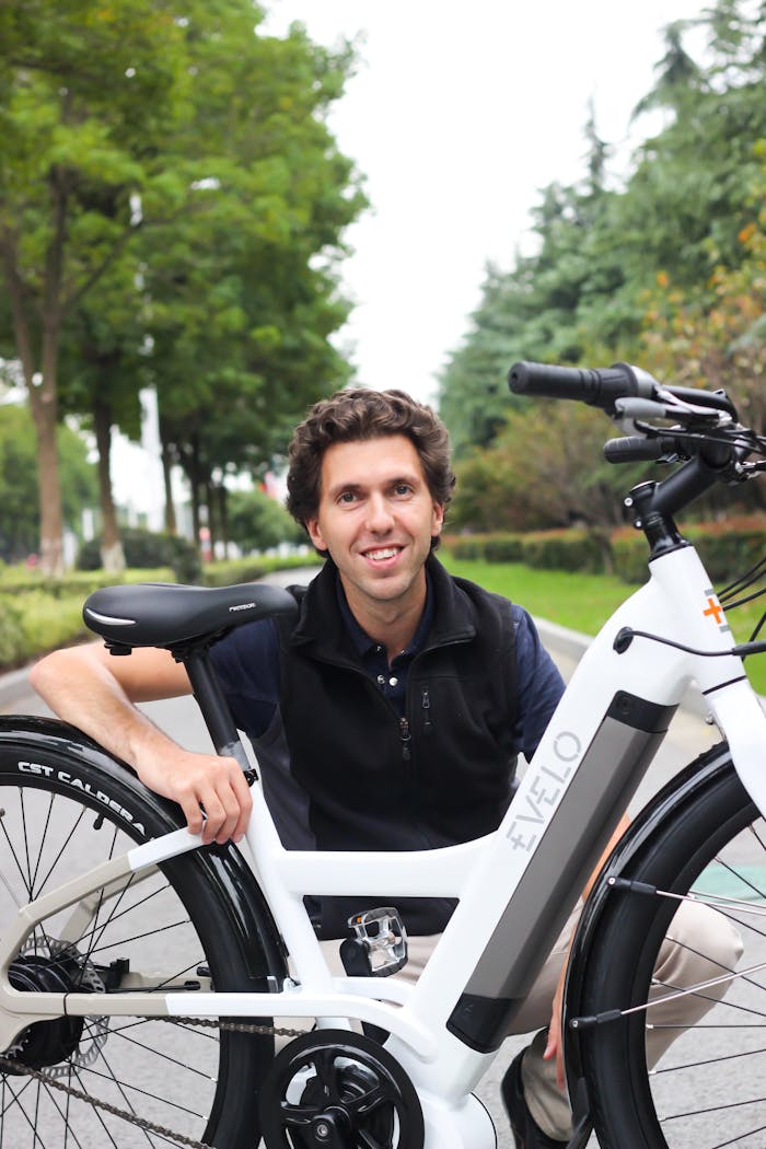 A cheerful man poses with an EVELO electric bicycle on a sunny day.